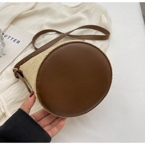 Detail of the round leather base and woven straw texture of this bucket bag