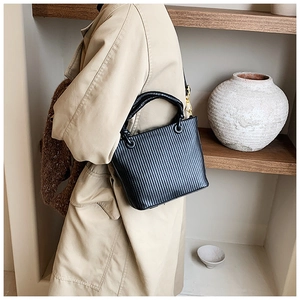 Detailed view of the black pleated bucket bag with metallic gold hooks and sleek texture