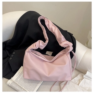 Detail of light pink baguette bag with soft pleated shoulder strap on minimalist outfit