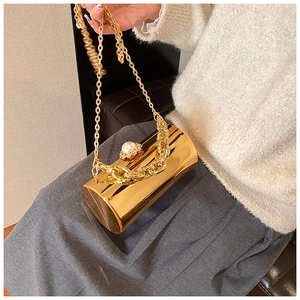 Detail of gold acrylic cylinder evening bag with pearl clasp and chain strap