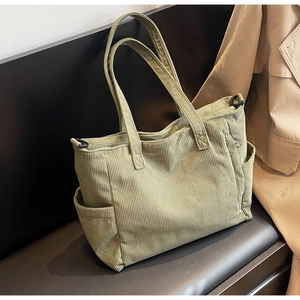 Detail view of corduroy tote bag with side pockets and fine textured fabric in olive green