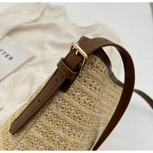 Detailed shot of the woven straw texture and premium brown leather strap with gold buckle