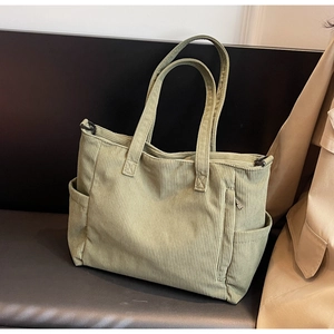 Detail of light green corduroy tote bag with side pockets on a stylish leather seat