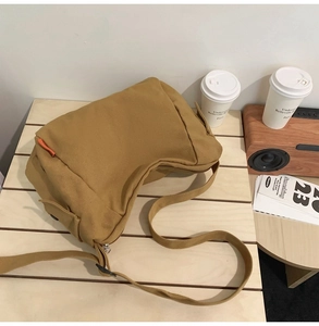 Vue détaillée du sac bandoulière en toile jaune moutarde sur une table en bois