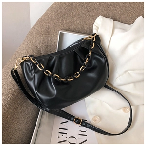 Detail of black pleated cloud bag featuring metal chain strap and soft leather texture