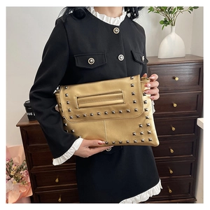 Dettaglio della pochette dorata con borchie quadrate e cinturino in stile retrò