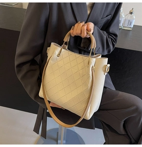 Detail of beige quilted leather tote with brown handles and gold hardware accents