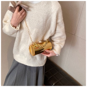 Detail of gold mirror cylinder bag with pearl clasp and chunky chain on knit sweater