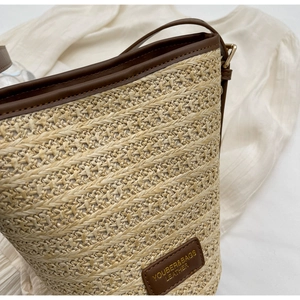 Close-up of woven straw texture and brown leather strap on a summer bucket bag