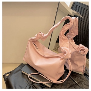 Detail of light pink baguette bag featuring ruffled shoulder strap and soft PU leather