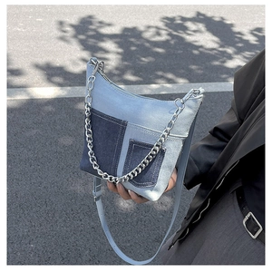 Detail of denim patchwork bucket bag with silver chain and leather strap on street