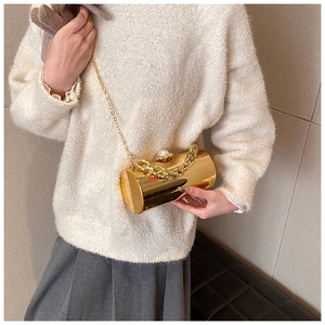 Detail of gold acrylic cylinder evening bag featuring pearl clasp and chain straps