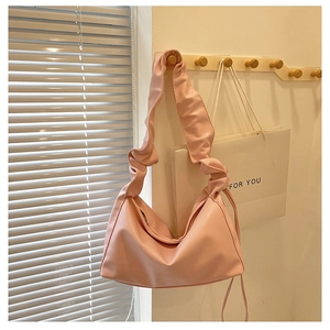 Detail of pink pleated strap croissant bag hanging in a bright indoor home setting