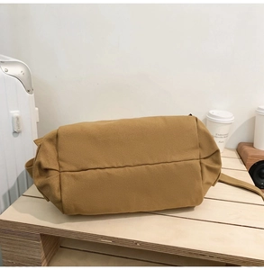 Détail de la couture renforcée du fond d'un sac bandoulière en toile marron pour homme