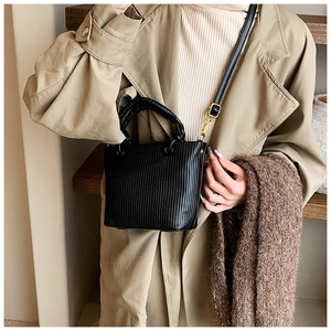 Close-up of black pleated bucket bag with fine vertical stripes and gold metal hardware