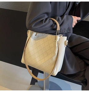 Close-up of beige quilted leather bucket bag with brown handle and metal zipper detail