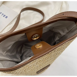 Detail view of woven straw bucket bag with magnetic closure and herringbone fabric lining