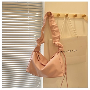 Detail of soft pink hobo bag featuring ruched strap and drawstring side accents