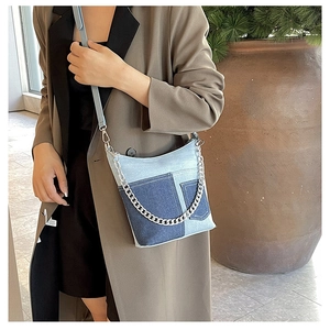 Detail shot of the patchwork denim crossbody bag with vintage blue tones and silver chain strap