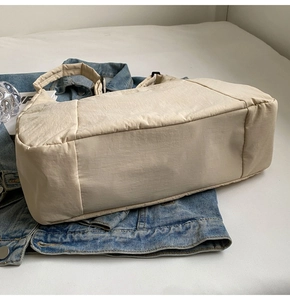 Detail of beige nylon tote bag material texture placed on a blue denim jacket