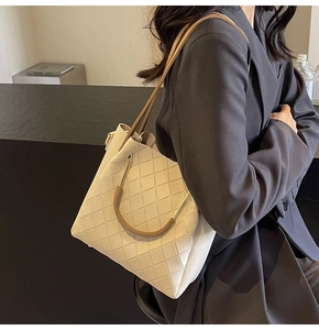 Detail of cream woven leather tote showing the ring handle and diamond stitching texture