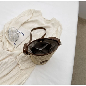 Top view of woven straw bucket bag showing fabric lining with zipper and slide pockets