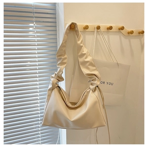 Detail of soft cream-colored pleated shoulder bag strap with smooth faux leather texture