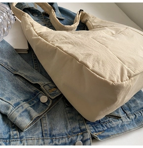 Detail view of cream quilted nylon tote bag with puffer texture and wide shoulder strap