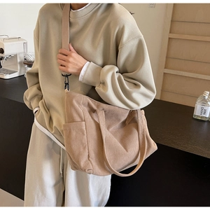 Detailed texture of khaki corduroy tote bag worn cross-body in a cozy cafe setting