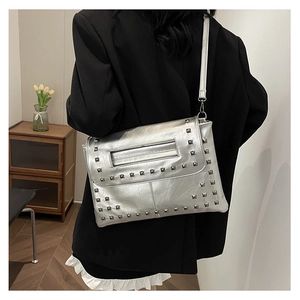 Dettaglio di una borsa a tracolla argento con borchie e blazer nero elegante