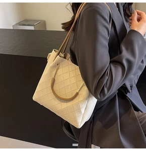 Close-up of cream woven leather bucket bag with metallic handles and quilted pattern