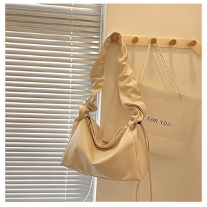 Close-up of cream pleated shoulder strap on a soft minimalist faux leather baguette bag