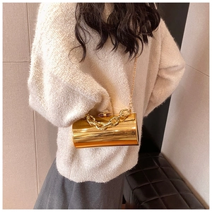 Fashionable mirror gold cylindrical clutch with chunky chain strap on a stylish outfit