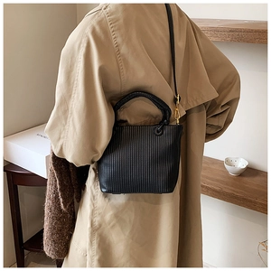 Detailed close-up of a black pleated bucket bag with vertical textures and gold hardware