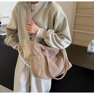Detail view of corduroy tote bag featuring side pocket design and detachable canvas strap