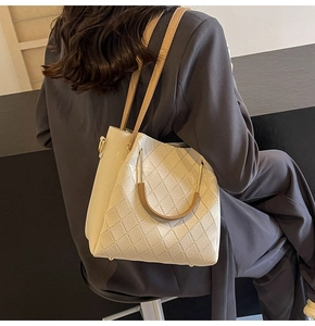 Beige quilted tote bag with dark handles shown on shoulder for daily commute style