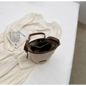 Top view showing woven bucket bag interior with magnetic closure and brown leather trim