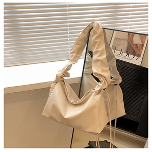 Detail of creamy white pleated cloud shoulder bag featuring a soft leather knotted strap