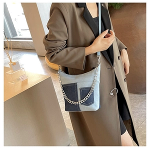 Detail of light blue patchwork denim shoulder bag with silver chain strap and half-moon shape