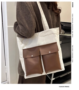 Detail of canvas tote bag featuring two brown front pockets with silver snap buttons