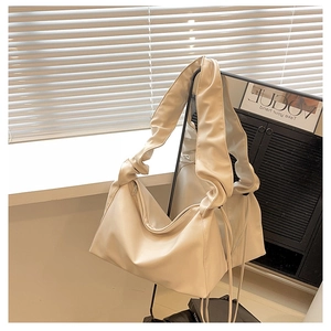 Detail of soft cream white pleated shoulder bag with elegant ruching on the wide strap