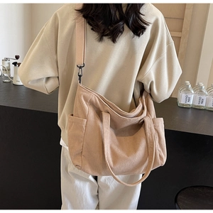 Corduroy tote bag in beige with side pocket and adjustable strap shown on model's back