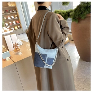 Detail of blue denim patchwork shoulder bag with silver metal chain on model