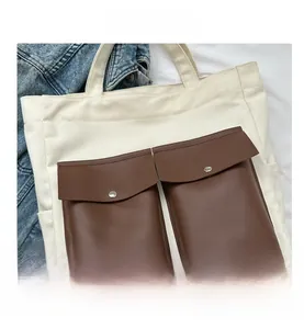 Close-up of cream canvas tote bag with brown faux leather pockets and metal snap buttons