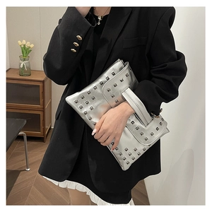 Pochette a busta argento metallizzato con borchie quadrate in un ambiente domestico
