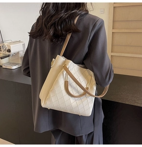 Detailed back view of a cream woven bucket bag with brown straps on a model