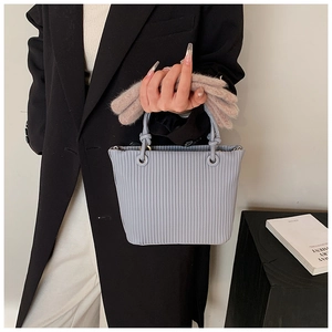 Detail of light blue pleated bucket bag featuring unique woven knot handles and faux leather