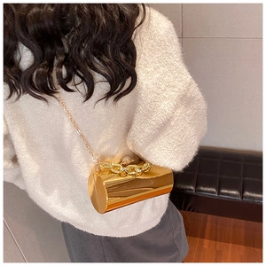 Detail of gold cylinder bag with chunky chain handle and large pearl clasp detail