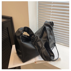 Macro view of black soft leather baguette bag with pleated handle on a white windowsill