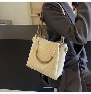 Detail of cream quilted hobo bag with unique metal handle and pebbled leather texture